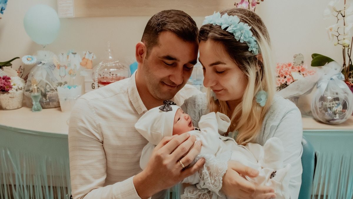 A loving couple embracing their newborn baby at an indoor baby shower.